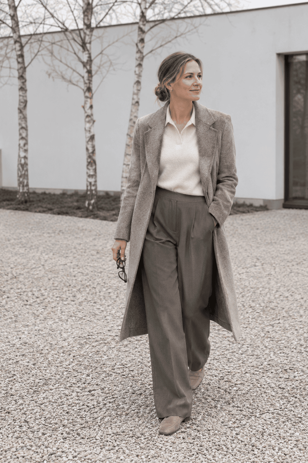old money winter color combination taupe and cream: long taupe wool-cashmere coat worn open over a cream cashmere polo sweater, taupe pleated wide-leg trousers and taupe suede loafers