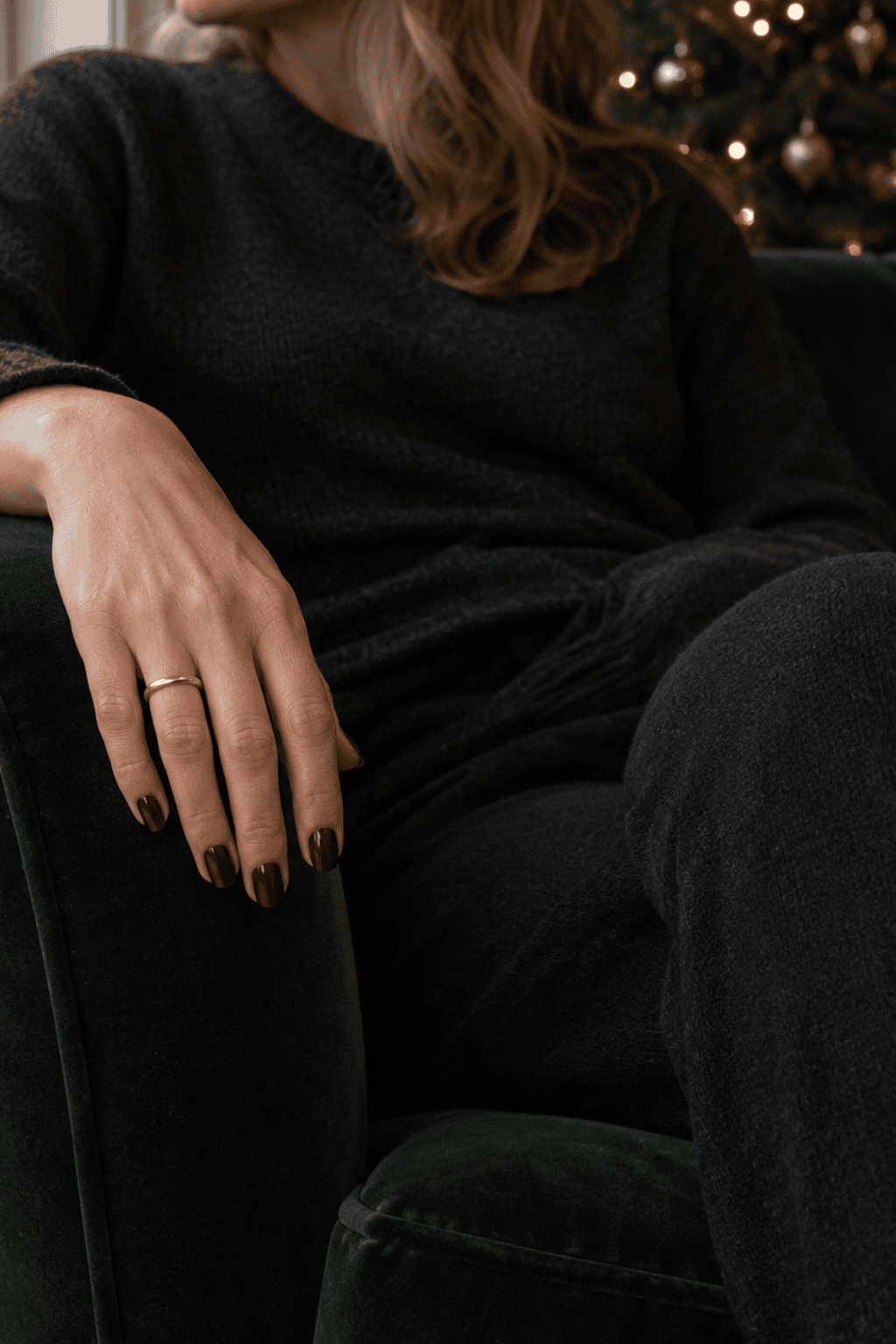 old money christmas nails in deep oxblood polish on short oval nails with a slim gold ring, hand draped over a green velvet armchair
