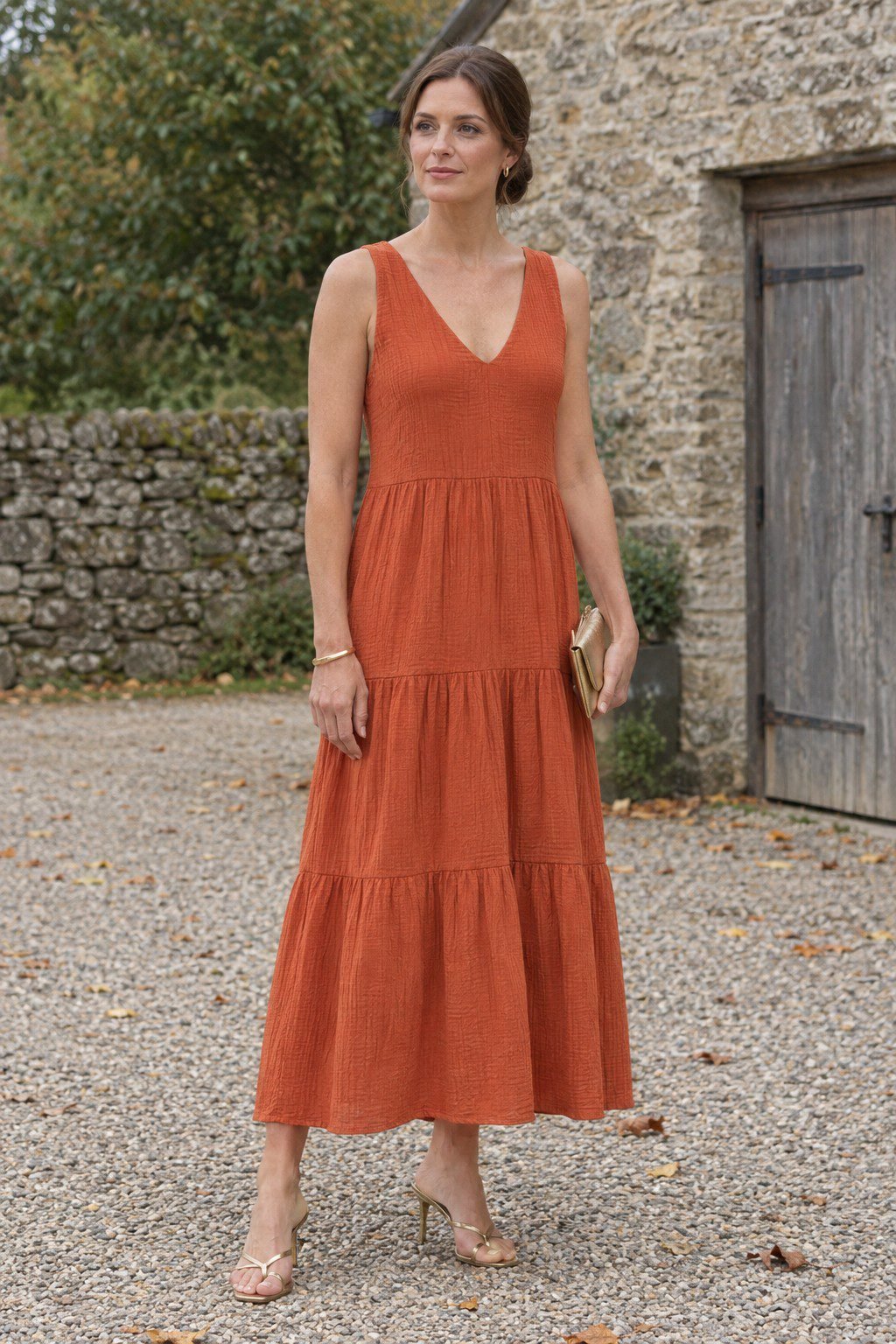 wedding guest outfit with gold bracelet: spiced orange tiered maxi dress and gold metallic sandals for a formal fall wedding